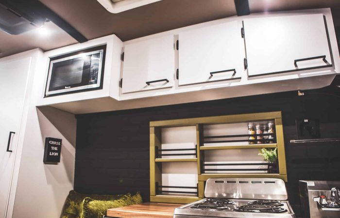 Custom built vans from Cruising Kitchens are the perfect way to "Live Life on Purpose." This Avril LaVan Off The Grid Overlander Van is complete with a custom grill featuring several plasma cut-out sasquatches, and a livable space including bed and L shaped bench seating.