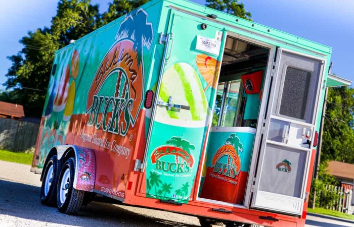 Bahama Bucks Shaved Ice Food Trailer is perfect for high volume shaved ice sales. This design layout utilizes state of the art ice block shavers and refrigeration with sleek diamond plating all over the interior and graphics package on the wrap exterior.