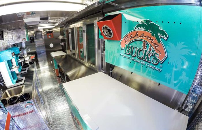 Bahama Bucks Shaved Ice Food Trailer is built by Cruising Kitchens custom to facilitate high quantity of customers with exceptional quality shaved ice. The design layout utilizes state of the art ice block shavers, refrigeration, storage, prep tables, sleek diamond plating all over the interior and graphics package on the wrap exterior as well as interior where there is no mistake that Bahama Bucks is the place to go for a refreshing sno-cone.
