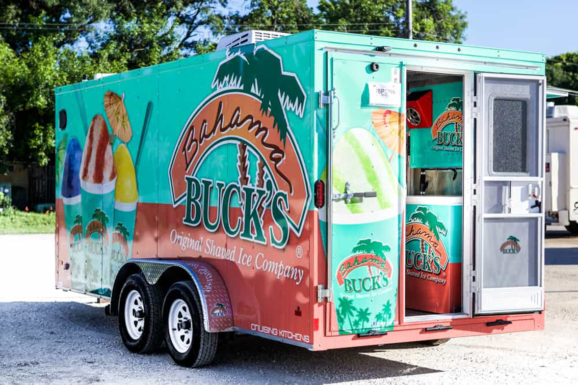 Bahama Bucks Shaved Ice Food Trailer is built by Cruising Kitchens to facilitate high quantity of customers with exceptional quality shaved ice. The design layout utilizes state of the art ice block shavers, refrigeration, storage, prep tables, sleek diamond plating all over the interior and graphics package on the wrap exterior as well as interior where there is no mistake that Bahama Bucks