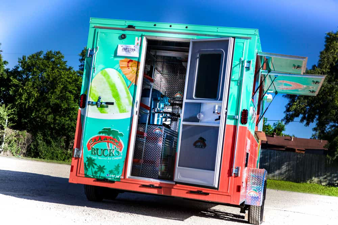 Bahama Bucks Shaved Ice Food Trailer is built by Cruising Kitchens to provide an exceptional experience for customers looking for a refreshing sno-cone. This sleek design features high-quality equipment and graphics to ensure that your business stands out from the competition.